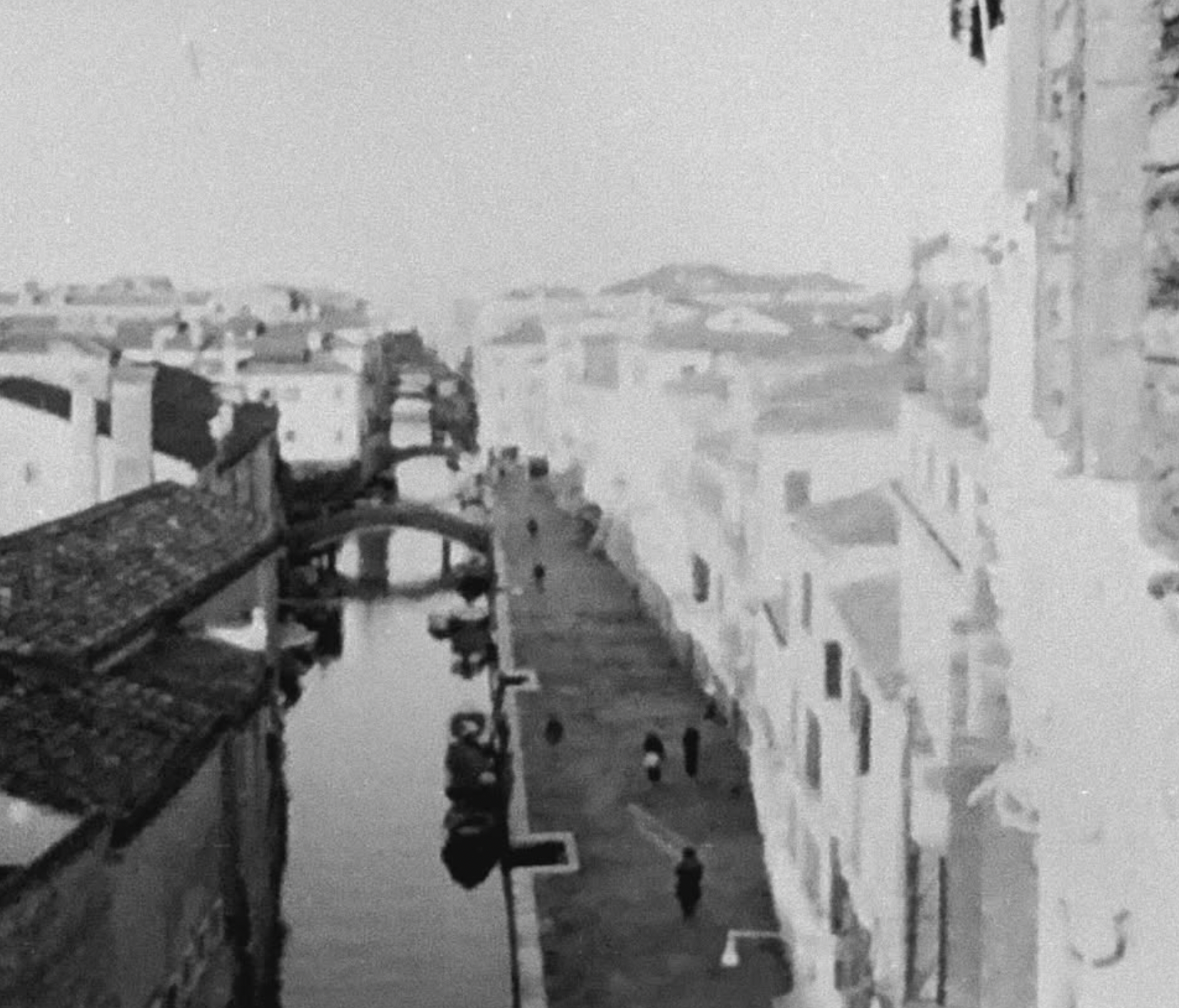 A grainy black-and-white view down a studio corridor, with a person in the distance
